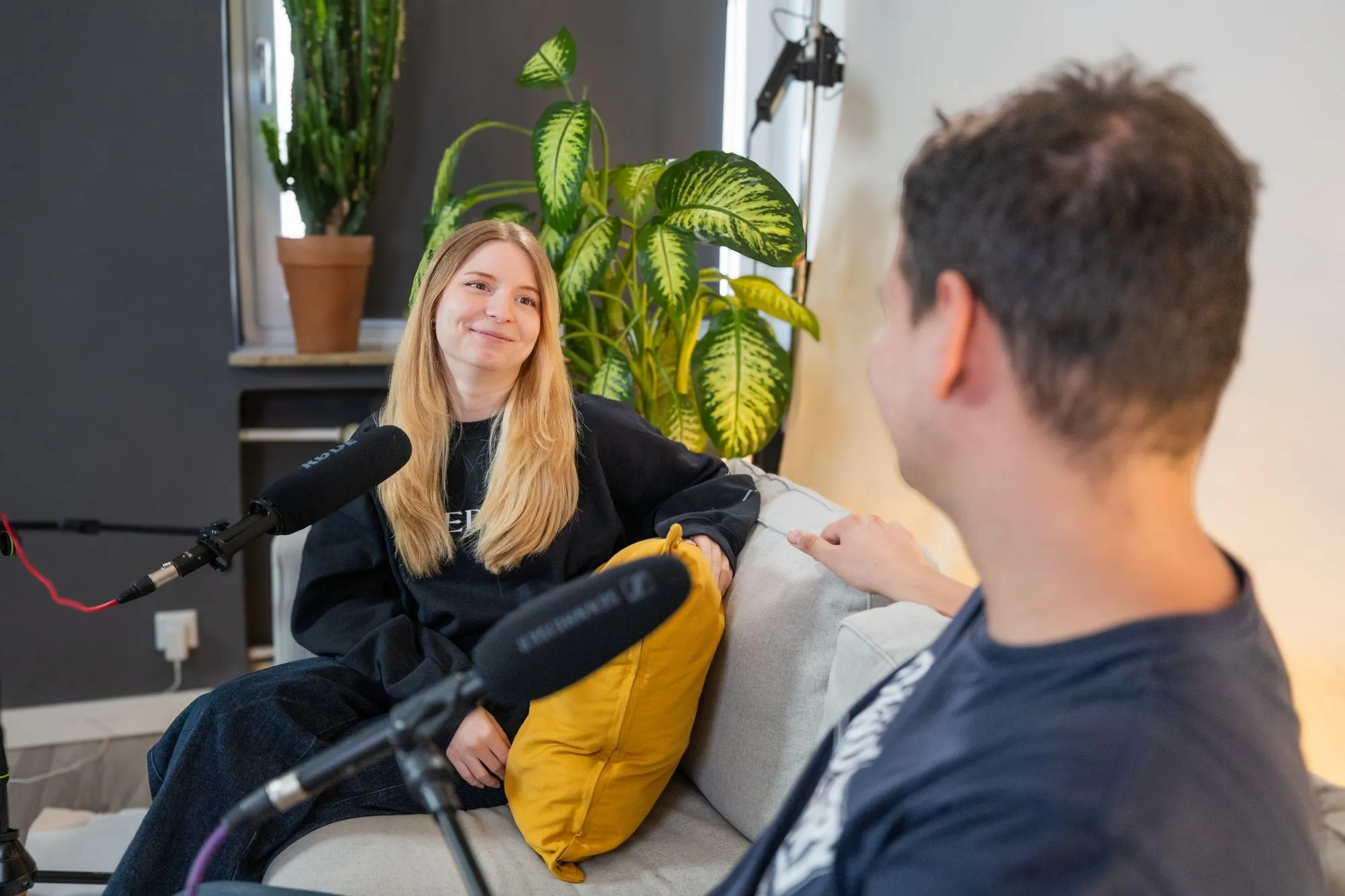 Podcast-Gast mit Mikrofon auf dem Sofa-Set im Podcast-Studio Essen